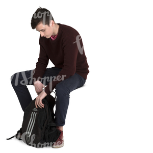 teenage boy sitting and looking for smth in his backpack