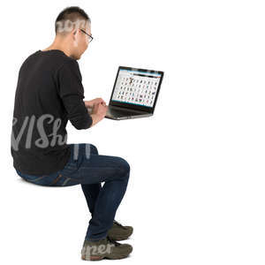 asian man sittin at the table and working with a laptop