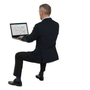 man in a suit sitting at his desk and working with a laptop