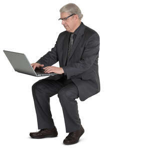 older businessman sitting at the desk and working with laptop