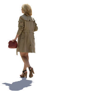 backlit woman in a trenchcoat walking