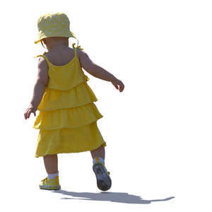 backlit baby girl in a yellow dress walking