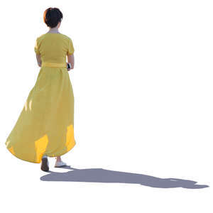 backlit woman in a long yellow dress walking