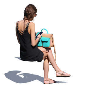 woman in a black summer dress sitting and checking her phone