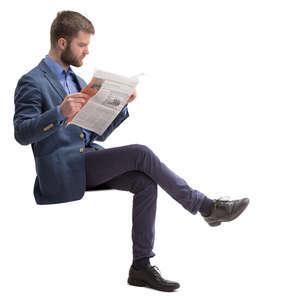 man in a suit sitting and reading a newspaper