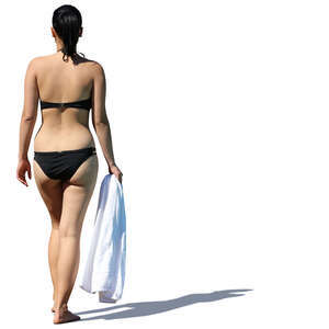 woman in a black bikini walking with a towel in her hand