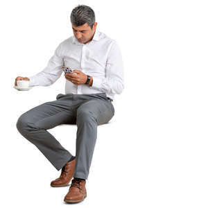 man in a suit sitting in a cafe and drinking coffee