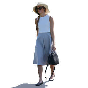 backlit woman with a summer hat walking
