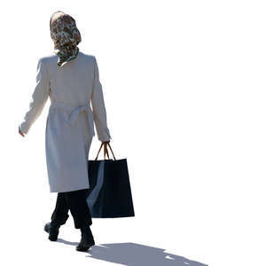 backlit woman with a headscarf walking