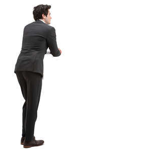 man in a black suit leaning on a railing