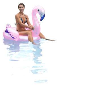 woman floating on a pink flamingo in a pool