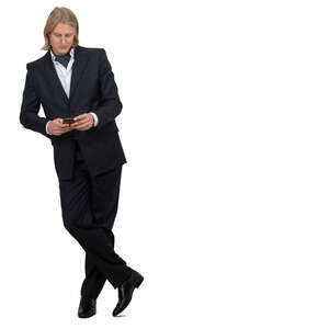 man in a suit leaning on a counter and checking his phone