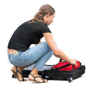 woman squatting and packing her suitcase