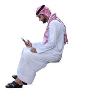 arab man in traditional clothing sitting and texting