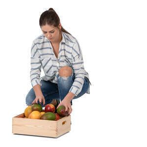 woman squatting and putting fruits in a box