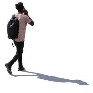 backlit man walking and talking on a phone