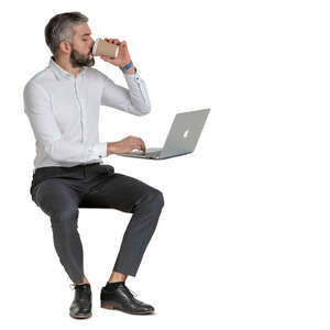 man sitting at an office desk and drinking coffee