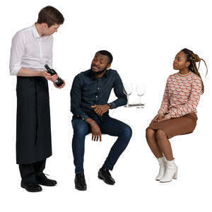 cut out waiter showing wine to the couple sitting in a cafe