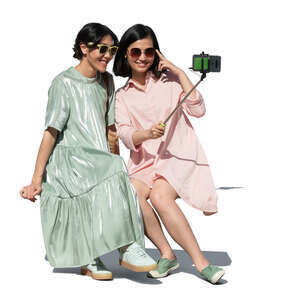 two cut out young asian women sitting and taking a selfie