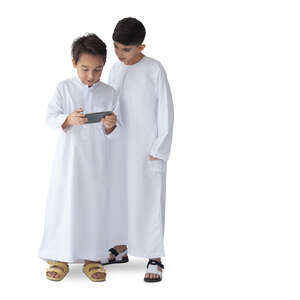 two cut out arab boys dressed in kandoras standing and watching tablet