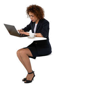 cut out woman with a copmuter sitting at a table and drinking coffee