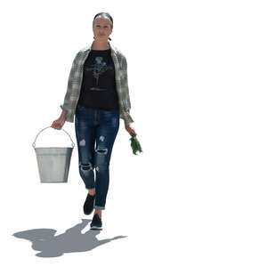 cut out backlit woman working in a garden walking and carrying a bucket