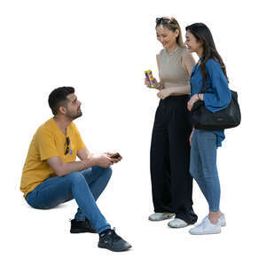 cut out man sitting and talking to two women standing beside him