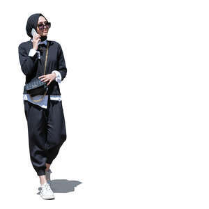 cut out young muslim woman walking and talking on a phone