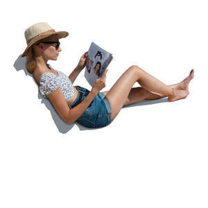woman lying on a sofa outside and reading a magazine