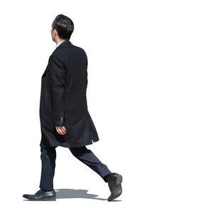 asian businessman wearing a suit and a black overcoat walking