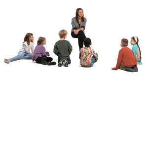 group of children stting on the ground and listening to their teacher