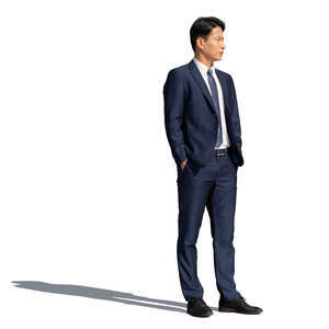 asian man wearing a dark suit standing hands in his pockets
