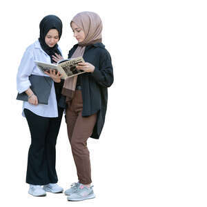 two muslim girls standing and reading a book