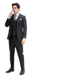 man in a black suit standing and talking on a phone