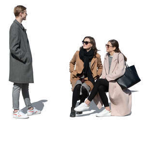 two women sitting and talking to a young man