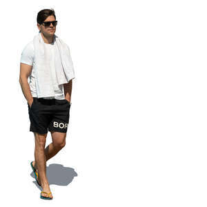 man in shorts and flipflops and carrying a towel walking