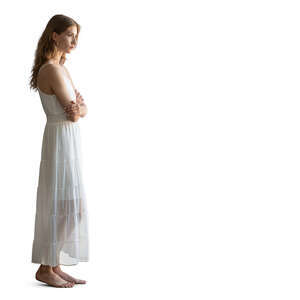 woman in a white dress standing barefoot by the window