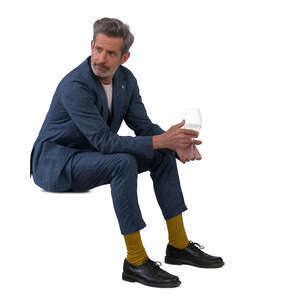 older man in a suit sitting and drinking wine