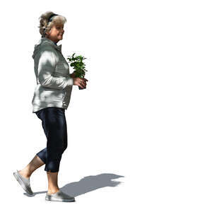 elderly woman with a plant walking in the garden