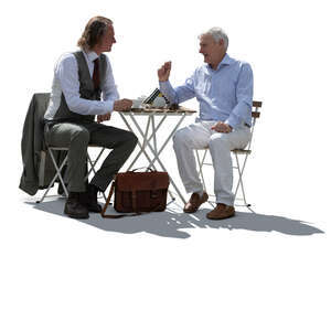 two backlit men sitting in a cafe