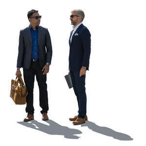 two backlit businessmen standing and talking