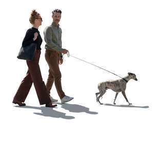 backlit man and woman walking with a dog