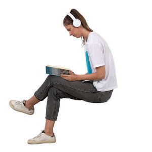 woman with headphones sitting and reading a book