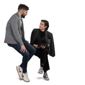 man sitting on a desk and talking to a woman sitting beside her