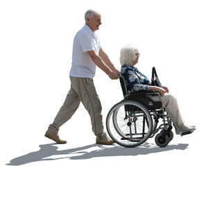backlit man pushing a woman in a wheelchair