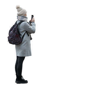 woman with a hat and backpack taking a picture with her phone