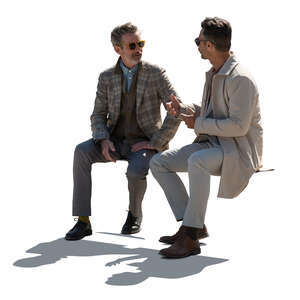two backlit gentlemen sitting and talking