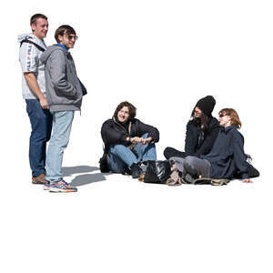 two men standing and talking to a group of people sitting on the ground