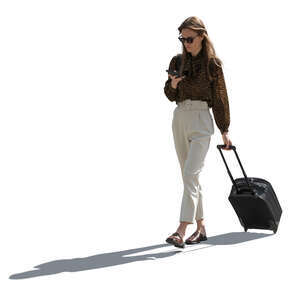 backlit woman with a suitcase walking and texting