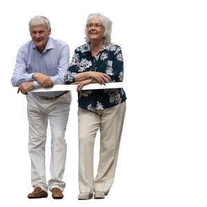 two senior people standing on a balcony and leaning on a railing
